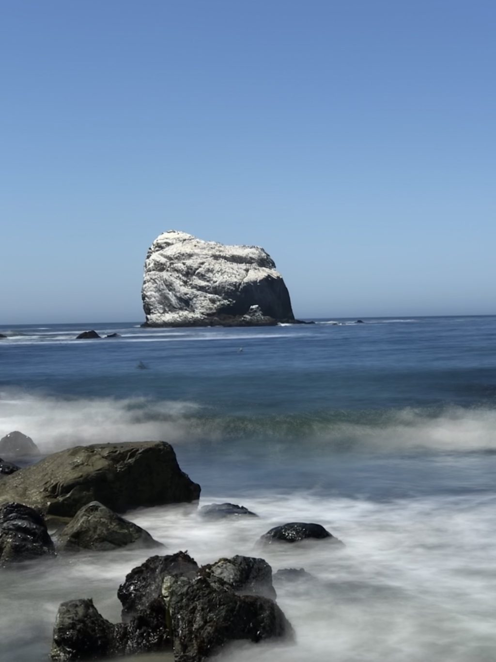 Silky surf around the tide rocks at Sand Dollar Beach, Plaskett Rock brilliant white against the blue.