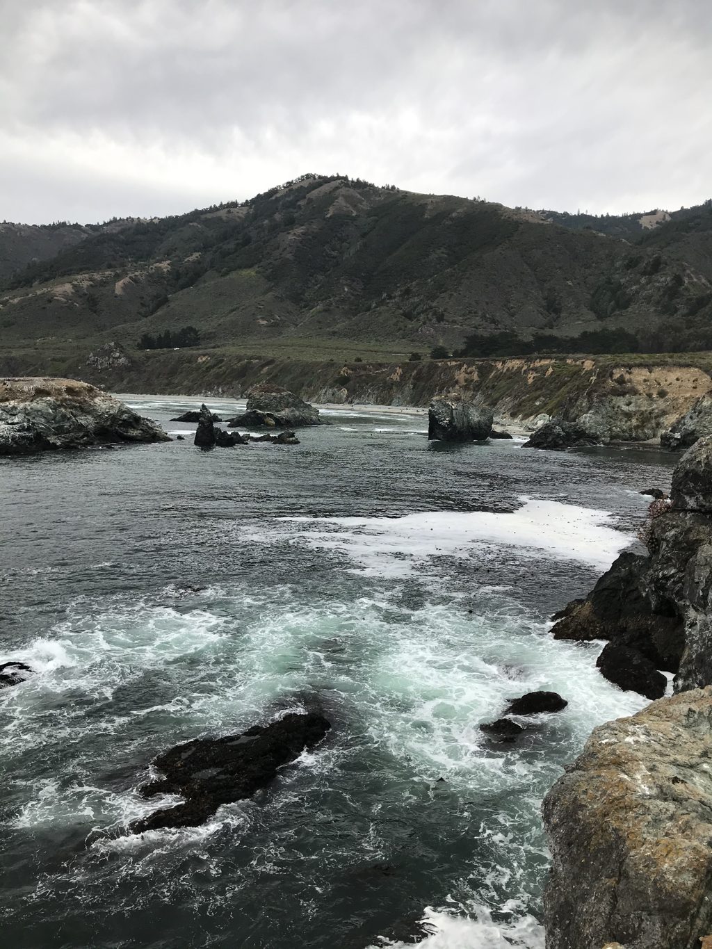 The same water today. Bill "Bull Plaskett" Alderson photographed the cove at Plaskett Rock in 2023, standing out on the rocks near where the landing cable once ran — the anchorage empty, the surf unchanged.